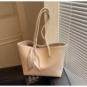 Close-up of cream white tote bag with lychee texture and a floral silk scarf detail