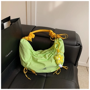 Détail du sac plissé vert avec anse chouchou jaune et accessoire de charme en fleur