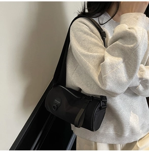 Detail of black nylon barrel crossbody bag with rubber logo patch and smooth zipper