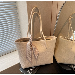 Detail of cream leather tote bag featuring a decorative scarf and pebble grain texture