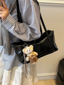 Glossy black underarm baguette bag with cute teddy bear charm for daily commuting style