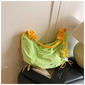 Gros plan sur le sac en nylon vert clair plissé avec bretelles jaunes et pendentif fleur