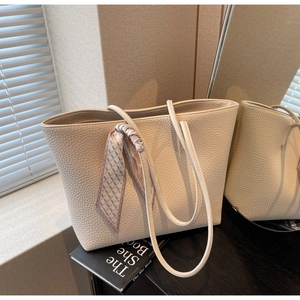 Detail of pebbled leather tote bag with elegant silk scarf decoration and slim handles