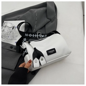 Détail du sac cylindre en cuir blanc avec large bandoulière imprimée mode