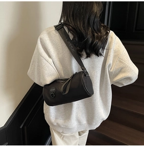 Rear view of a black cylinder crossbody bag featuring a wide 'CLASSIC' lettered strap