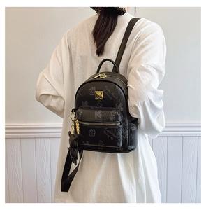 Detail of black lychee texture mini backpack with teddy bear print and plush bear charm