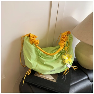 Vue macro du sac plissé vert en nylon avec cordons jaunes et logo de la marque