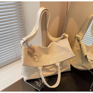 Detail of cream white tote bag with pearl bow charm on a decorative book in warm lighting