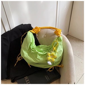 Détail du sac hobo en nylon plissé vert avec breloque fleur jaune et anse satin