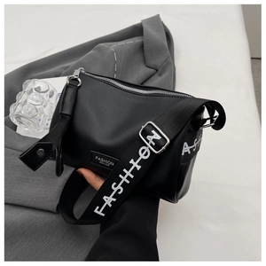 Détail d'un sac bandoulière noir en cuir grainé avec large sangle à lettres fashion