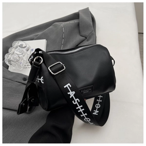 Détail du sac polochon en cuir noir grainé avec large bandoulière lettrée FASHION