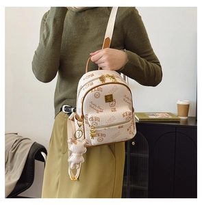 Detail of a beige bear print mini backpack with brown leather strap and bear charm