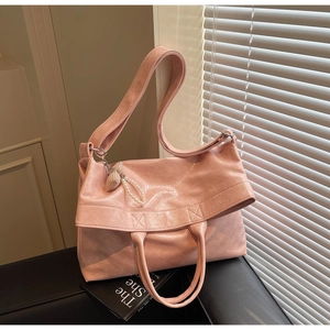Detailed view of pink crinkled leather tote bag with heart charm and pearl chain decoration