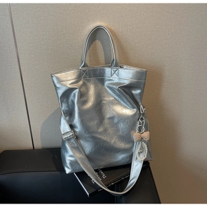 Close-up of silver tote bag with pleated texture, pearl charm and plaid bow detail