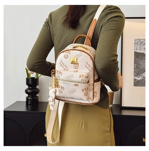 Detail of a beige mini backpack with brown leather trim and cute teddy bear charm accessory