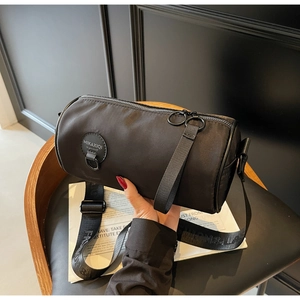 Detail of black oxford cylinder bag with adjustable woven strap and branded label