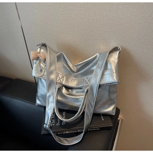 Detail of silver metallic tote bag with pearl heart charm and brown bow accessory