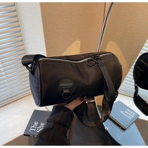 Detail of black nylon barrel bag featuring a silver zipper and sporty wide strap