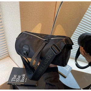 Detailed macro of waterproof nylon barrel bag with wide woven strap and silver hardware
