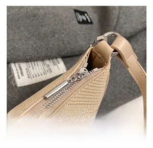 Close-up of shiny silver metal zipper and woven texture on a beige shoulder bag
