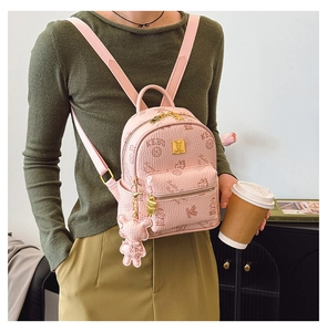 Detail of pink small backpack featuring all-over logo print and cute bear charm accessory