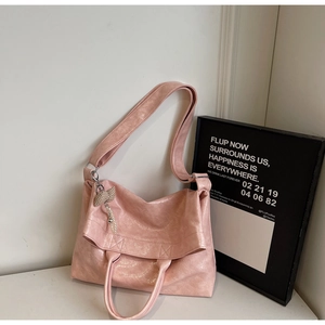 Detailed view of pink tote bag with chic bow and pearl charm against a clean wall