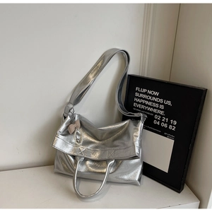 Close-up of silver tote bag showing crinkled texture, bow charm, and pearl pendant