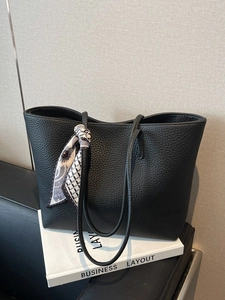 Black pebbled leather tote bag with silk scarf on book, minimalist business commute style