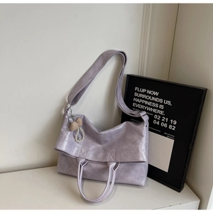 Detail of lavender tote bag featuring pleated patent leather and a pearl heart charm