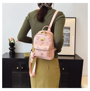 Close-up of pink synthetic leather backpack featuring embossed bears and gold zippers