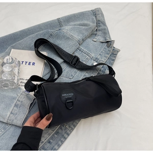 Detail of black cylinder crossbody bag with leather logo and embossed wide shoulder strap