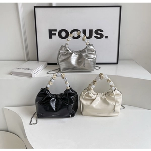 Detailed view of pleated dumpling bags in silver and beige with acrylic bead handles