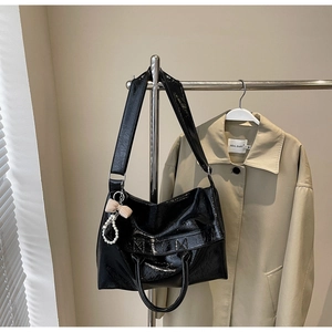 Detail of glossy black wax leather tote bag featuring pearls and bow pendant