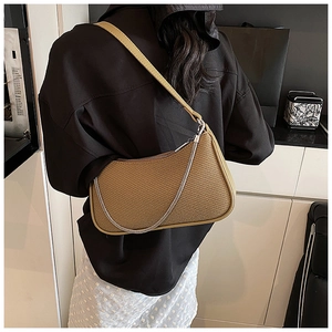 Detail of khaki woven shoulder bag with silver chain and smooth leather strap on model