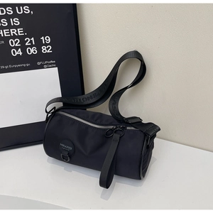 Detail of adjustable wide shoulder strap with embossed lettering on black cylinder bag