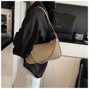 Close-up of khaki woven shoulder bag with delicate metal chain and leather strap