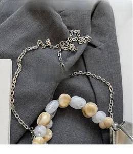 Detail of marble resin beads and silver metal chain strap on a modern dumpling bag
