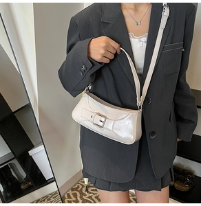 Detail of minimalist beige baguette shoulder bag with leather strap and buckle detail