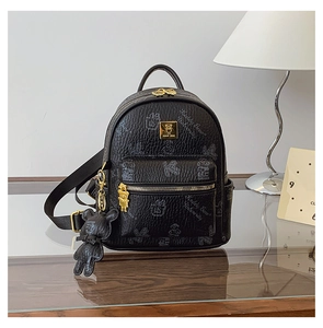 Close-up of black leather mini backpack with bear embossing and gold metal bear logo