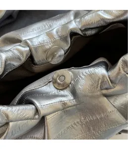Macro shot of silver pleated handbag featuring a durable metallic magnetic snap closure