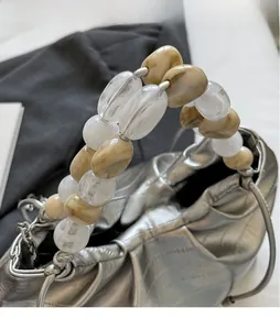 Close-up of silver pleated dumpling bag featuring unique chunky marble and white beaded handle