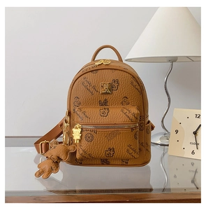 Detailed view of brown litchi leather backpack with bear print and golden zipper