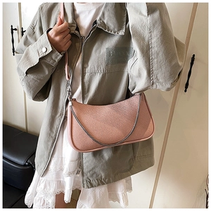 Pink woven texture shoulder bag with metal chain detail shown on a female model