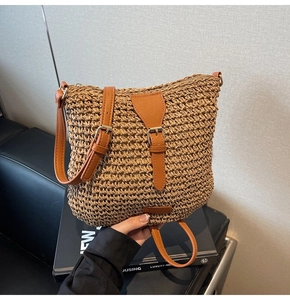Detail of handcrafted brown straw bag with synthetic leather strap and gold-tone buckle