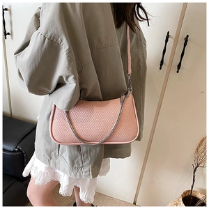 Close-up of pink woven shoulder bag featuring a silver chain strap and refined texture