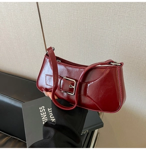 Close-up of a deep red glossy baguette bag featuring a stylish silver buckle and sleek texture