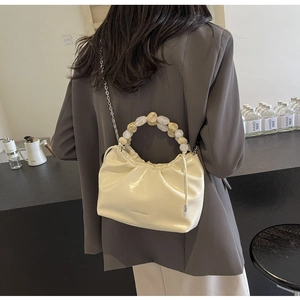 Detail of cream pleated dumpling bag with marble beads and metallic chain strap