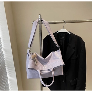 Detail of light purple oil wax leather tote with pearl bow charm and wide shoulder strap