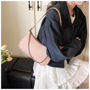Detail view of pink woven texture underarm bag with silver chain strap on a model