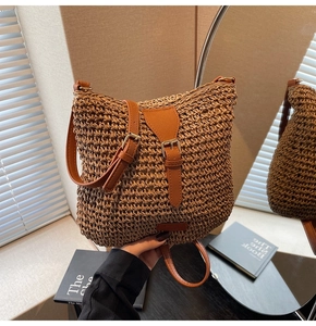 Detail of hand-woven straw crossbody bag with brown leather strap and buckle